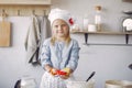 Little girl in a white shef hat cook the dough for cookies