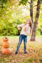 Little girl in a white sweater and jeans on a background of green textural natural background. A girl dancing with pumpkins near t Royalty Free Stock Photo