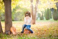 Little girl in a white sweater and jeans on a background of green textural natural background. A girl sits on pumpkins and covers Royalty Free Stock Photo