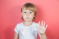 Little girl in white t-shirt with breast cancer warning ribbon showing stop sign Royalty Free Stock Photo