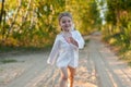 A little girl in a white traditional ÃÂhemise running in a scenic early autumn landscape