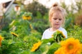 Little girl in white Tshirt, stands in field of sunflowers and smiles Royalty Free Stock Photo