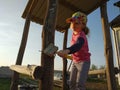 Little girl whitewash oak barrel of children`s slide on playground, sunset Royalty Free Stock Photo