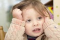 Little girl whose face and sweater is smudged with paint