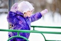 Little girl in winter clothes having fun on playground at the snowy winter day Royalty Free Stock Photo