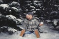 A little girl in winter clothes playing with snow on a snowy mea