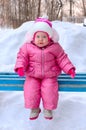 Little girl in winter outerwear sit on bench. Royalty Free Stock Photo