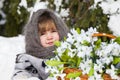 Little girl in a winter wood with the big basket of snowdrops