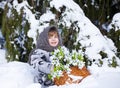 Little girl in a winter wood with the big basket of snowdrops