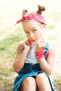Little girl wipes her mouth with a napkin. A child with a hair tail and a red bandana