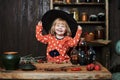 Little girl witch in black pointed hat and magical accessories. Halloween, the studio evening.