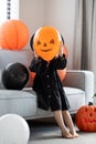 A little girl in a witch costume covers her face with an orange balloon. Children at the Halloween party. Royalty Free Stock Photo
