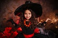 A little girl in a witch costume on a gloomy background scares people. Getting ready for All Saints Day. Halloween costume