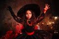 A little girl in a witch costume on a gloomy background scares people. Getting ready for All Saints Day. Halloween costume