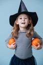 Little girl in witch hat holding two small pumpkins, she& x27;s dressed for halloween Royalty Free Stock Photo