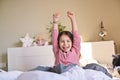 The little girl woke up. The child in his pajamas stretches in bed, smiling shows positive emotions.