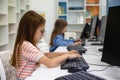 Little girl working on computer in school library. Royalty Free Stock Photo