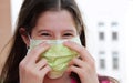 Little girl without worries fixes the green surgical mask for pr