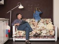 Little girl wrighting on the chalkboard doing English while her father working on his laptop sitting on the couch. Girl writing Royalty Free Stock Photo