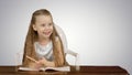 Little girl writes to writing-book on white background Royalty Free Stock Photo