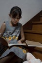 Little girl writing book and having cookie at stairway at home Royalty Free Stock Photo