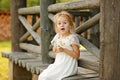 Little girl 5 years blonde sitting on a log home, holding hands