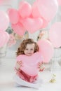 Cute six year old girl in pink dress with pink balloons in the shape of heart Royalty Free Stock Photo