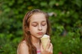 Little girl eat ice cream at an outdoor In a colorful striped bright dress. Sunny summer, hot weather Royalty Free Stock Photo