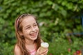 Little girl eat ice cream at an outdoor In a colorful striped bright dress. Sunny summer, hot weather Royalty Free Stock Photo