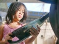 Little girl, 4 years old, cleaning a car using a portable handheld vacuum cleaner