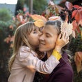 A little girl of 7 years old kisses and hugs her mother against the background of autumn leaves outdoors. The concept of happy Royalty Free Stock Photo
