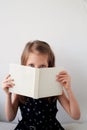 A little girl, 6 years old, looking over a book. Remote study, quarantine.On a white background.