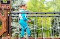 A little girl 5 years old plays on the playground, passes through the staircase labyrinths in the daytime