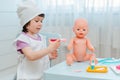 Little girl 3 years old preschooler playing doctor with doll. The child makes an injection toy. Royalty Free Stock Photo