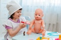 Little girl 3 years old preschooler playing doctor with doll. The child makes an injection toy. Royalty Free Stock Photo