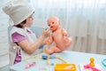 Little girl 3 years old preschooler playing doctor with doll. The child makes an injection toy. Royalty Free Stock Photo