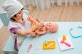 Little girl 3 years old preschooler playing doctor with doll. The child makes an injection toy. Royalty Free Stock Photo