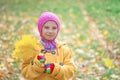 Little girl in yellow coat collects Royalty Free Stock Photo