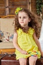 Little girl in yellow dress sits on old big ragged Royalty Free Stock Photo