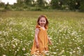 little girl in a yellow dress stands among a daisy field Royalty Free Stock Photo