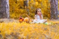 Little girl on yellow falling maple leaves background, fall outdoor.