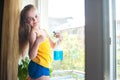 Little girl in shirt and blue shorts washes the windows at home. Daughter with a cat wash the window Royalty Free Stock Photo