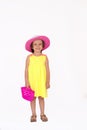 Little girl with yellow summer dress and pink hat holding a plastic toy bag, isolated Royalty Free Stock Photo