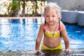 Little girl in a yellow swimsuit in a blue pool like a mermaid. kids concept, kids fashion.