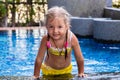 Little girl in a yellow swimsuit in a blue pool like a mermaid. kids concept, kids fashion.