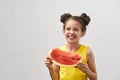 Little girl in yellow t-shirt, laughing merrily and holding slice of watermelon