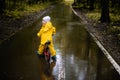 Little girl in yellow waterproof clothes on bike