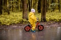 Little girl in yellow waterproof clothes with bike