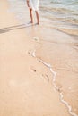 Little girle walking on sand beach leaving footprint in the sand. Beach travel