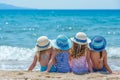 little girls in beautiful straw hats sit on the sand and look at the sea. girl friends are relaxing at sea. bright sunny day.